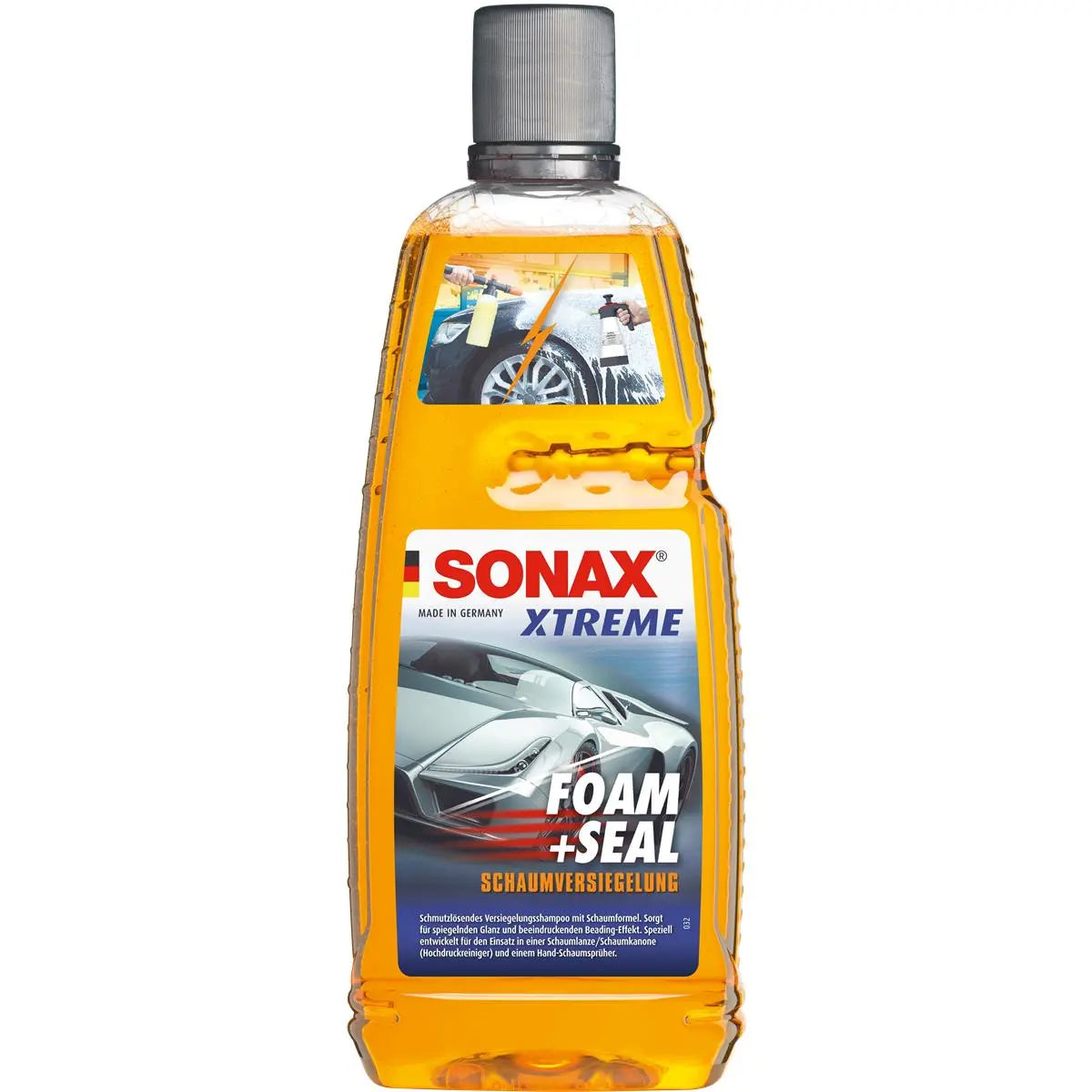 Ein Bild eines Sonax Xtreme Foam+Seal Shampoo & Versiegelung 1L Autoreinigungsprodukts der Marke SONAX in einer durchsichtigen Plastikflasche. Die orangefarbene Flüssigkeit im Inneren ist für die Fahrzeugwäsche und schmutzabweisende Konservierung bestimmt. Das Etikett zeigt ein Auto, das mit Schaum besprüht wird, was die doppelte Wirkung des Produkts als Waschen und Versiegeln veranschaulicht.